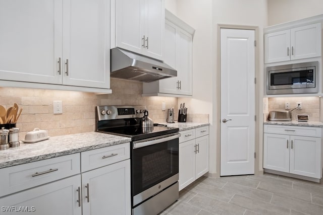 kitchen with tasteful backsplash, appliances with stainless steel finishes, light stone counters, and white cabinets