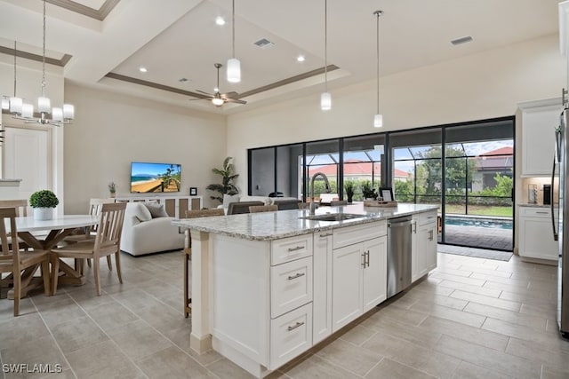 kitchen with sink, white cabinetry, a kitchen island with sink, light stone countertops, and ceiling fan with notable chandelier