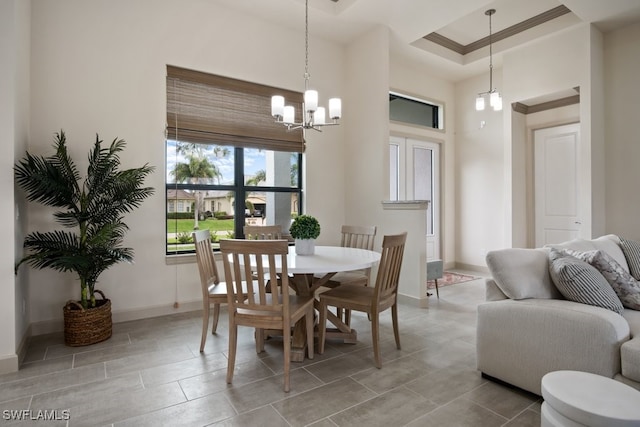 dining space with a raised ceiling, crown molding, and a chandelier