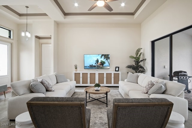 living room featuring ceiling fan and a raised ceiling