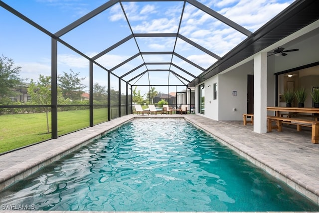 view of swimming pool with a lanai, a patio area, ceiling fan, and a lawn