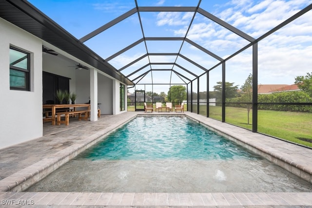 view of pool with a patio area, a lawn, ceiling fan, and glass enclosure