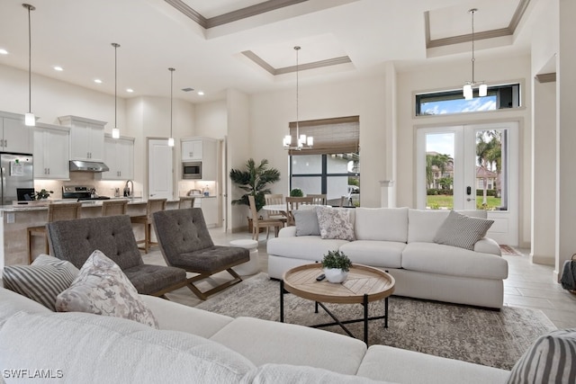 living room with crown molding, a towering ceiling, and a chandelier