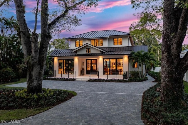 back house at dusk featuring covered porch