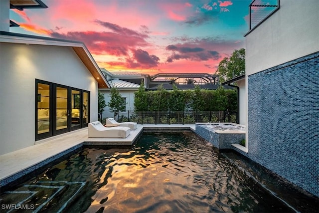 pool at dusk featuring a patio area and a jacuzzi