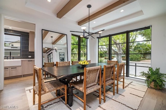 dining room featuring ceiling fan with notable chandelier, light wood-type flooring, beam ceiling, and sink