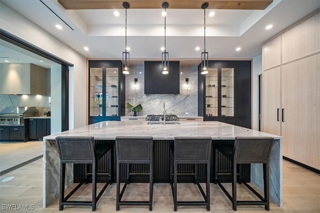 bar featuring light stone counters, a tray ceiling, and hanging light fixtures