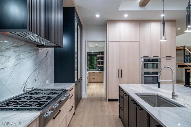 kitchen with appliances with stainless steel finishes, hanging light fixtures, light stone counters, sink, and backsplash