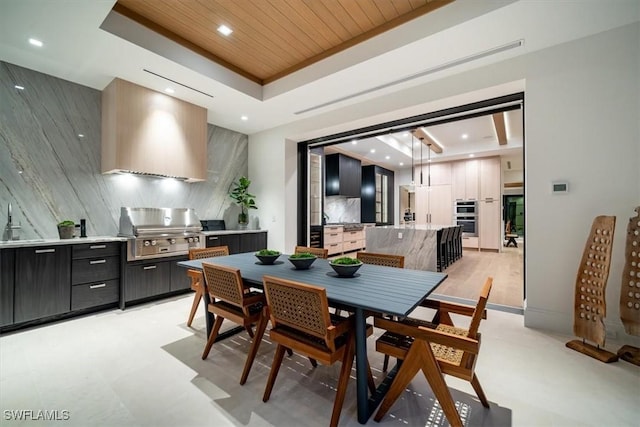 dining space with sink, a raised ceiling, and wood ceiling