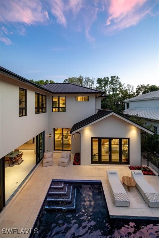 back house at dusk featuring a patio area and an outdoor living space