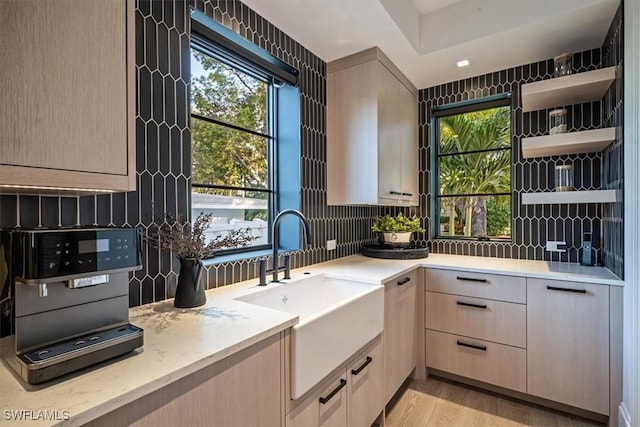 kitchen with sink, light wood-type flooring, tasteful backsplash, and light brown cabinets