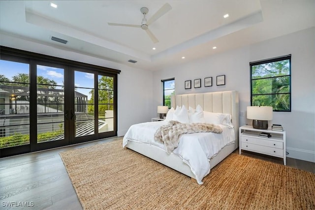 bedroom featuring access to outside, ceiling fan, and a tray ceiling