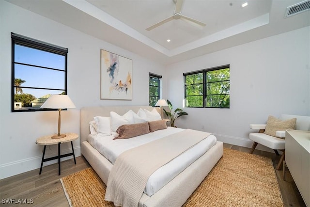 bedroom with a raised ceiling, ceiling fan, and hardwood / wood-style flooring