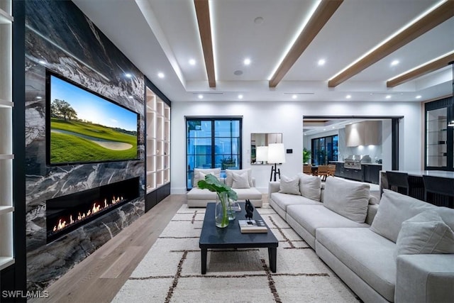 cinema room featuring light hardwood / wood-style flooring, beamed ceiling, and a fireplace