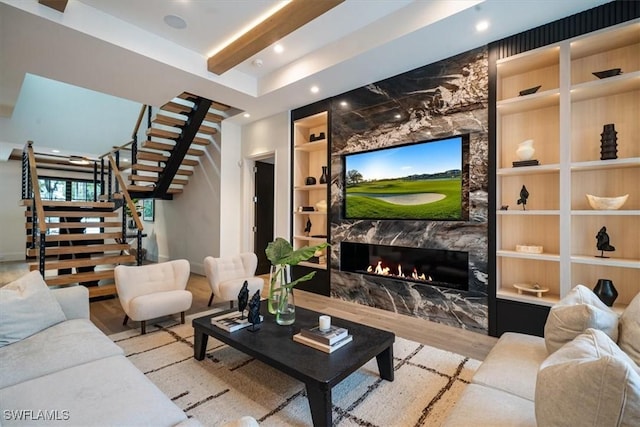 living room with built in shelves, a tiled fireplace, and light hardwood / wood-style flooring