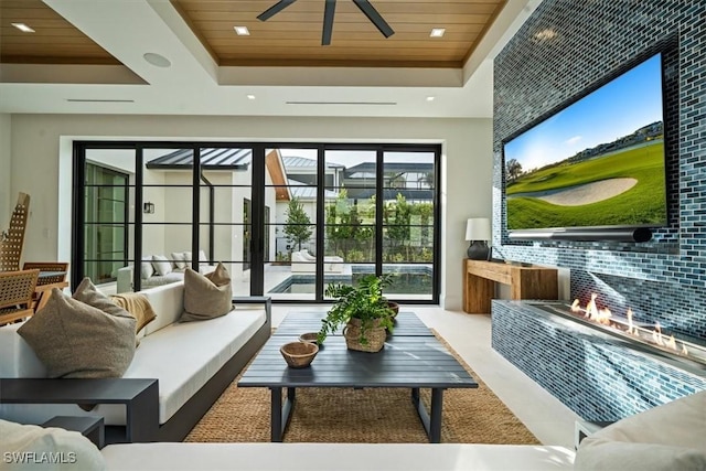 living room featuring a raised ceiling, ceiling fan, and wood ceiling