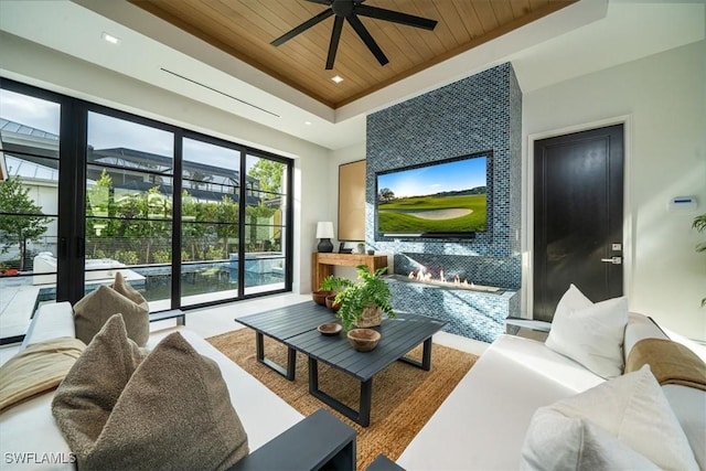 living room with ceiling fan, wood ceiling, and a raised ceiling