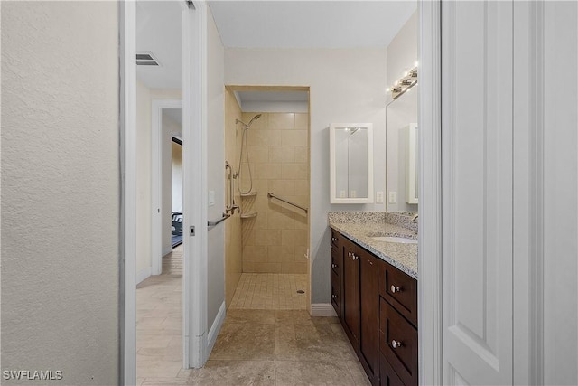 bathroom with tiled shower and vanity