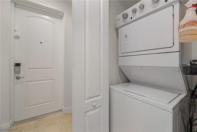 laundry room with light tile patterned floors and stacked washer / drying machine