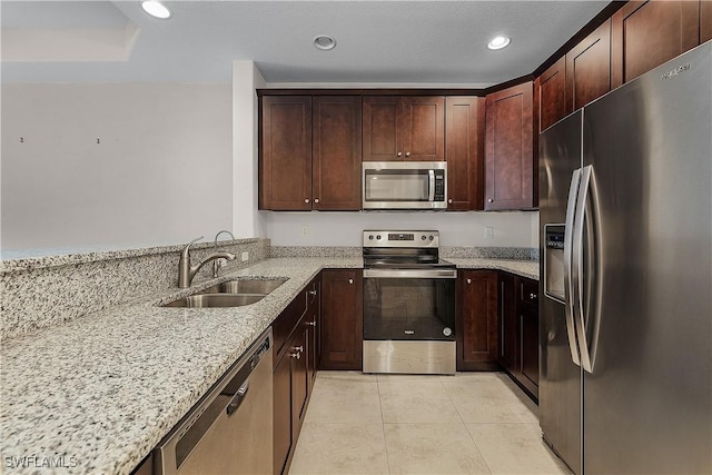 kitchen featuring appliances with stainless steel finishes, sink, light tile patterned flooring, and light stone countertops