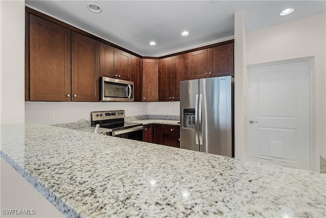 kitchen featuring appliances with stainless steel finishes, light stone counters, kitchen peninsula, and dark brown cabinetry