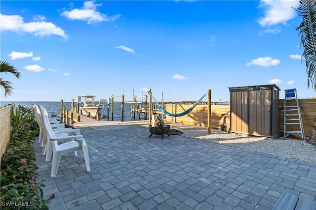 view of play area featuring a fire pit, a boat dock, a water view, and a patio