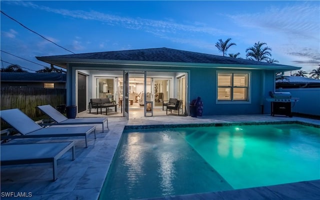 back house at dusk featuring a patio and a fenced in pool