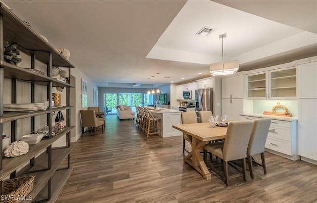 dining area featuring ceiling fan, sink, and dark wood-type flooring