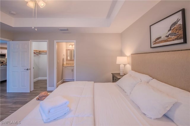 bedroom featuring ensuite bathroom, a walk in closet, ceiling fan, dark hardwood / wood-style flooring, and a closet