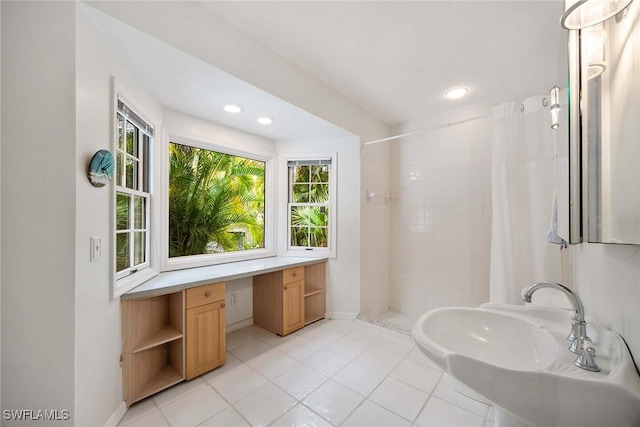 bathroom featuring tiled shower, tile patterned floors, and sink