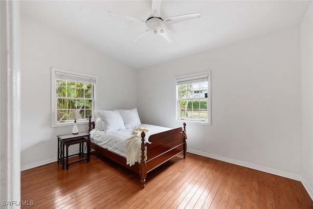 bedroom with multiple windows, wood-type flooring, vaulted ceiling, and ceiling fan