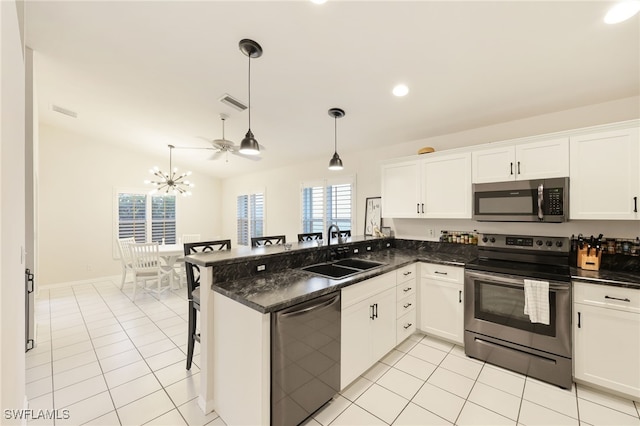 kitchen featuring white cabinets, a peninsula, hanging light fixtures, stainless steel appliances, and a sink