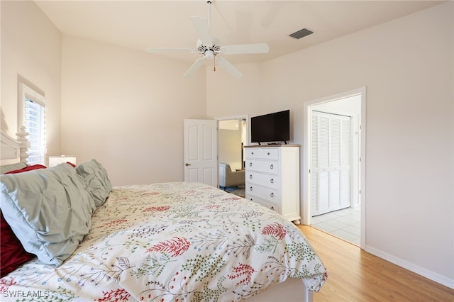 bedroom featuring baseboards, visible vents, a ceiling fan, light wood-style flooring, and high vaulted ceiling