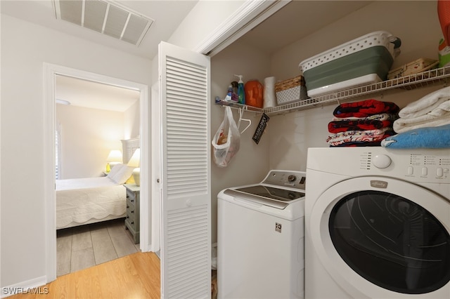 laundry area with washing machine and dryer, laundry area, visible vents, and light wood finished floors