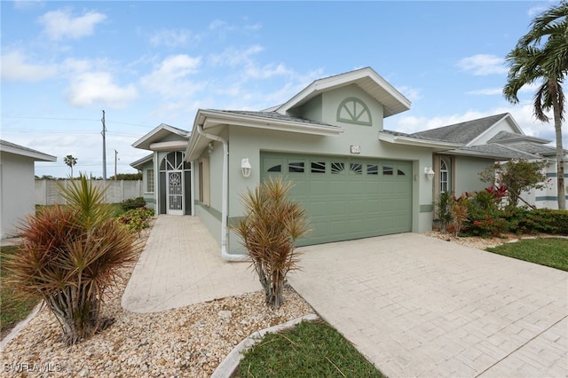 view of front of property with decorative driveway, an attached garage, and stucco siding