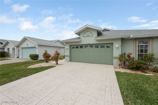 ranch-style house with a front lawn, decorative driveway, an attached garage, and stucco siding