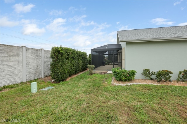 view of yard with glass enclosure and a fenced backyard