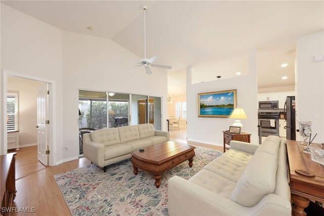 living room featuring vaulted ceiling, ceiling fan, and light hardwood / wood-style floors