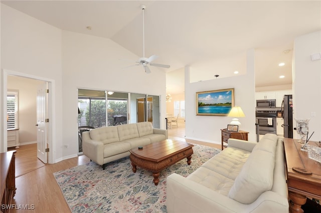 living room with ceiling fan, high vaulted ceiling, and light hardwood / wood-style flooring