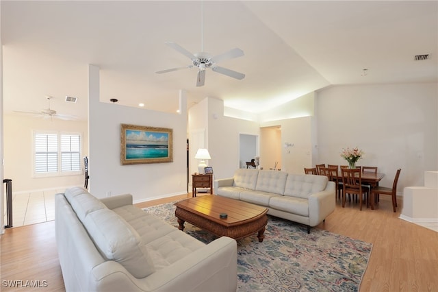 living area featuring light wood-type flooring, visible vents, vaulted ceiling, and a ceiling fan