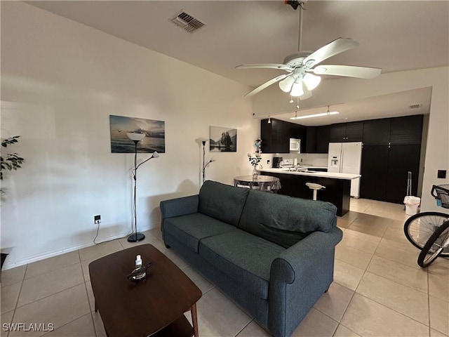 living room with ceiling fan, vaulted ceiling, and light tile patterned flooring