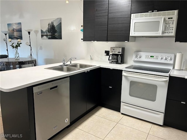 kitchen with light tile patterned flooring, sink, kitchen peninsula, and white appliances