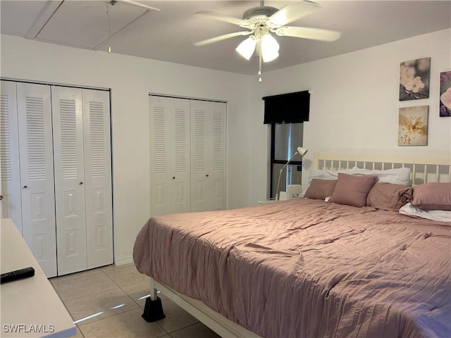 tiled bedroom with ceiling fan and two closets