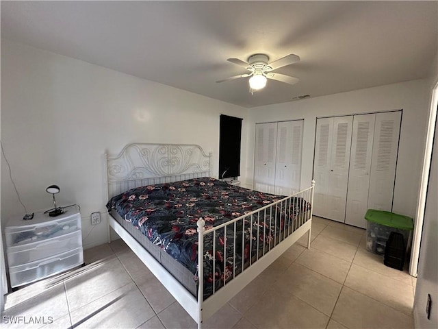 tiled bedroom featuring ceiling fan and multiple closets