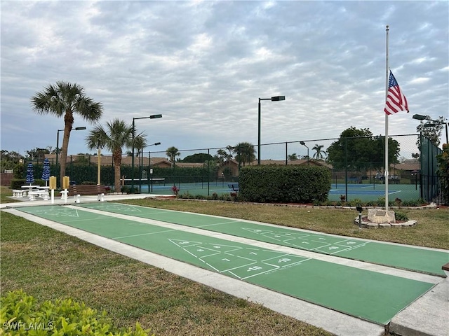 view of property's community with tennis court and a lawn