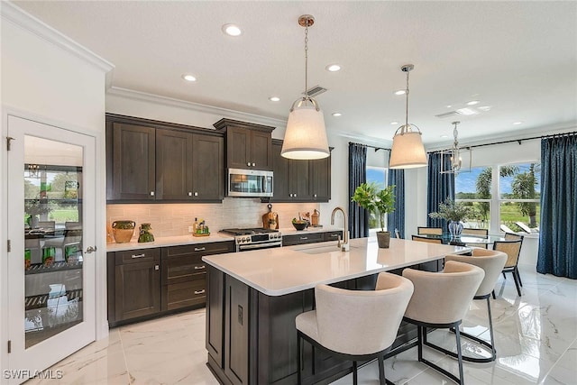 kitchen featuring a center island with sink, sink, hanging light fixtures, dark brown cabinets, and stainless steel appliances