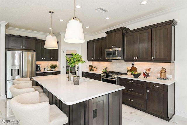 kitchen with pendant lighting, dark brown cabinets, a kitchen island with sink, and appliances with stainless steel finishes