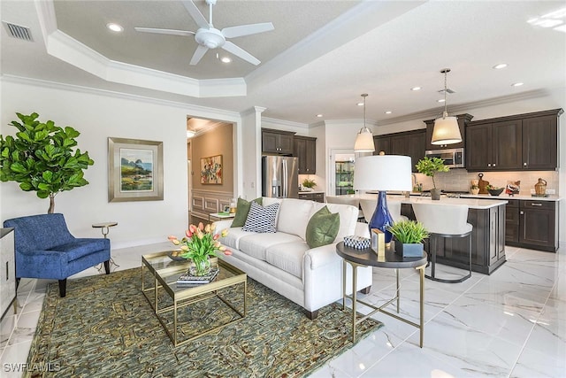 living room featuring a raised ceiling, ceiling fan, and crown molding