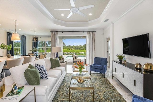 tiled living room featuring ceiling fan with notable chandelier, a raised ceiling, and ornamental molding