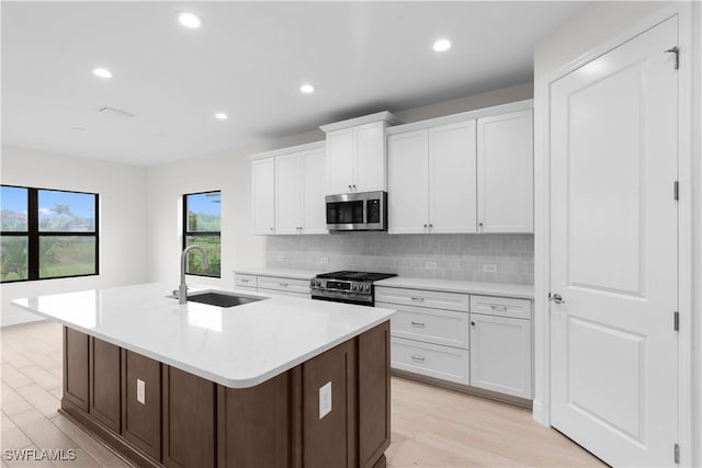 13617 Heritage Preserve Dr, Fort Myers, FL 33905 - kitchen featuring a sink, stainless steel appliances, tasteful backsplash, a center island with sink, and white cabinetry